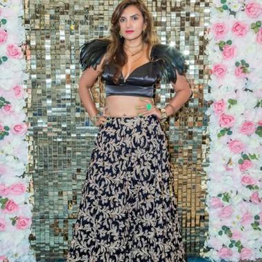 In an embroidered navy-and-gold lehenga and feathered top against a gold sequin and floral backdrop at the Ms. Bharat New England pageant.