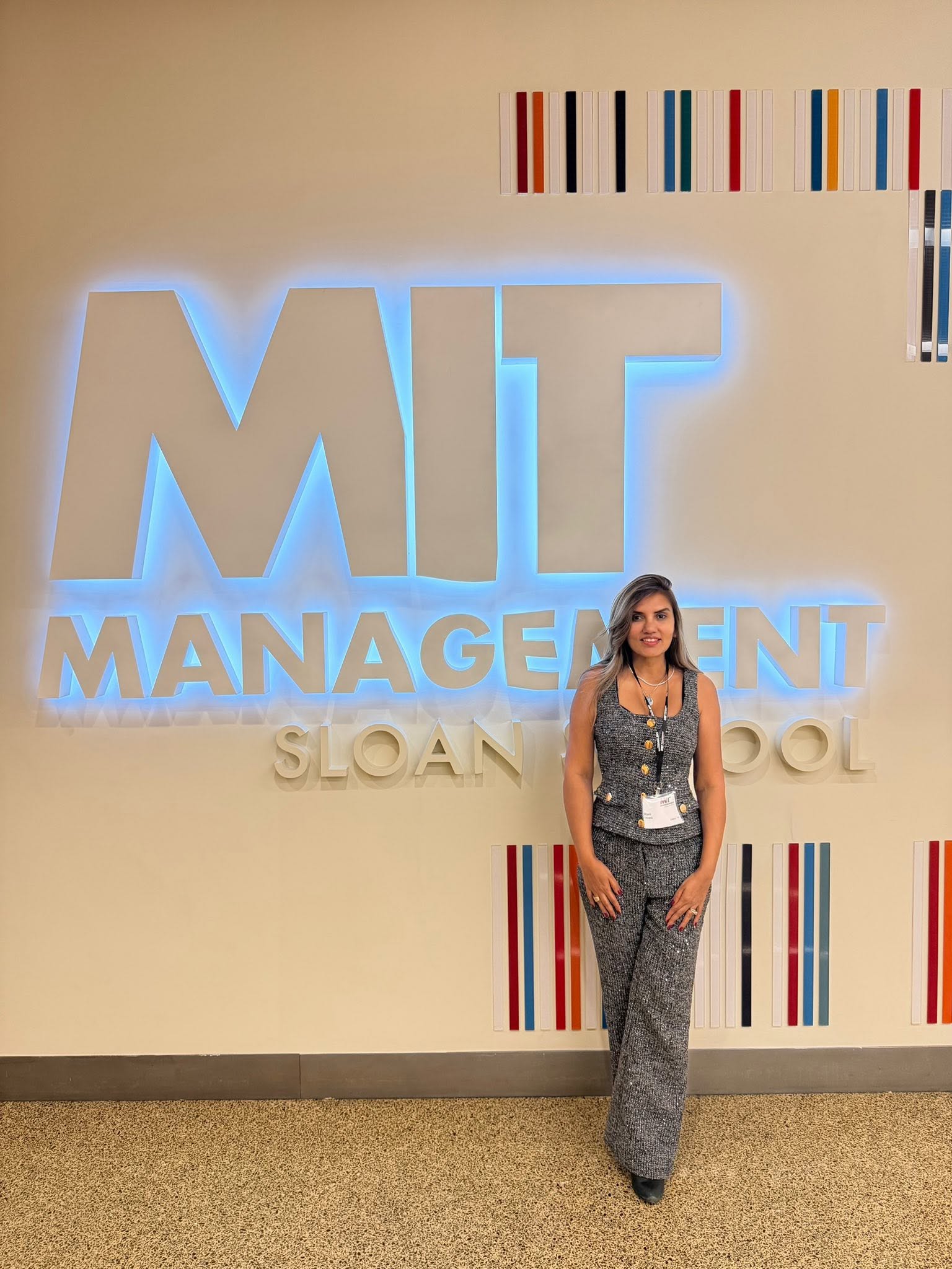 Dipali Trivedi standing in front of the illuminated MIT Management Sloan School sign in Cambridge